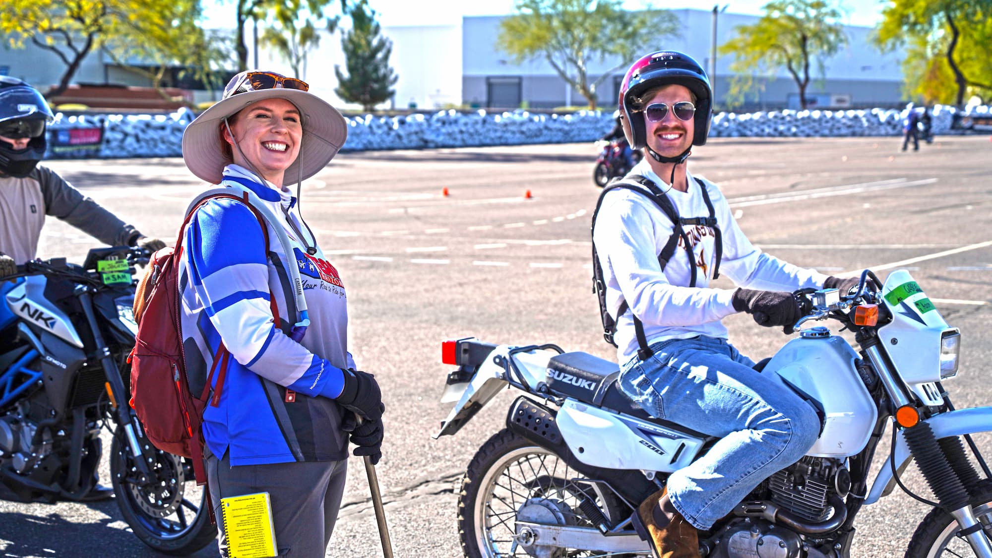 people learning to ride a motorcycle smiling at the camera
